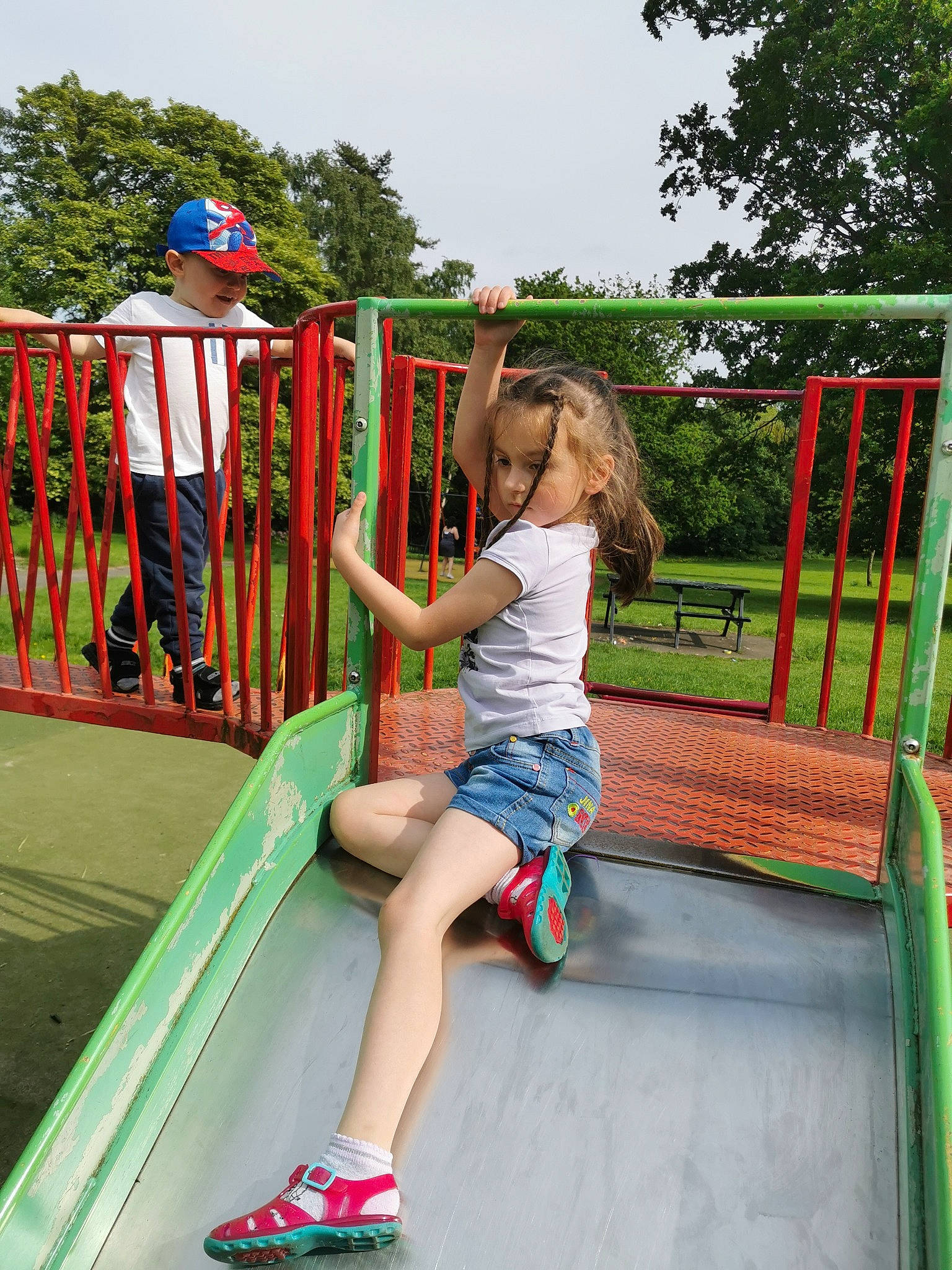 Maya is registered to the contest to win money with this photo: chute, city, electric_blue, fun, grass, headwear, human_settlement, leisure, outdoor_play_equipment, outdoor_recreation, person, plant, play, playground, playground_slide, recreation, shorts, sky, summer, toddler