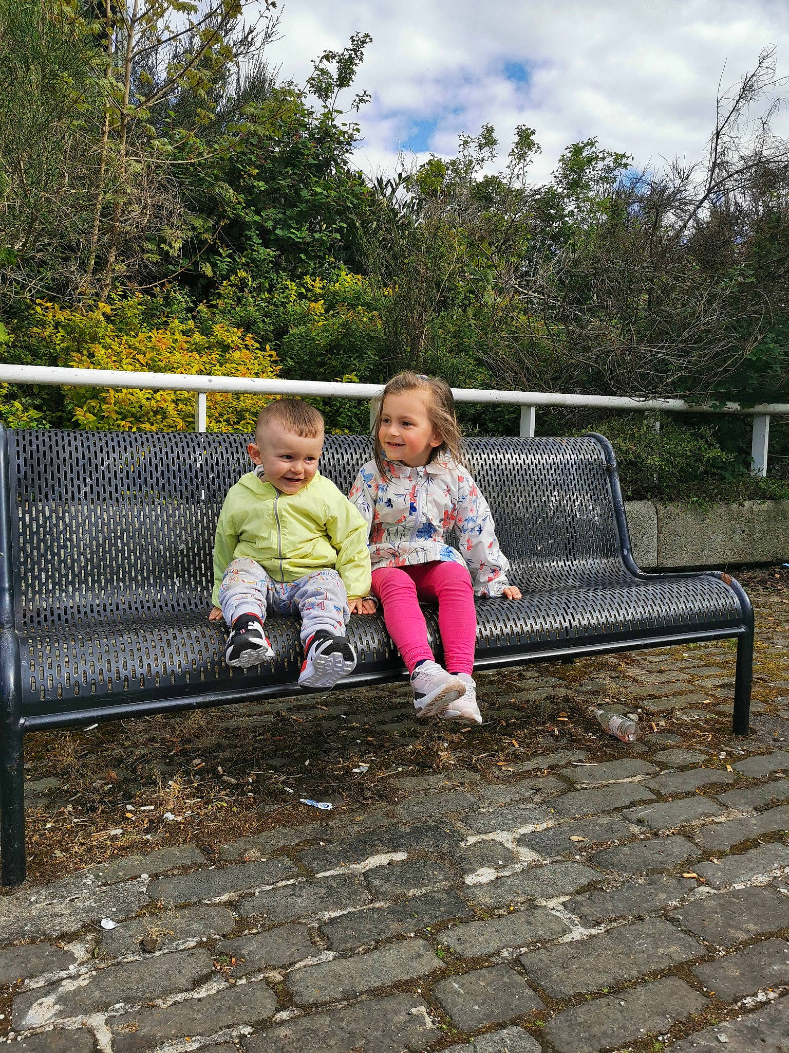 Maya is registered to the contest to win money with this photo: bench, botany, city, fun, garden, grass, joy, leaf, leisure, outdoor_bench, outdoor_furniture, people_in_nature, person, plant, recreation, road_surface, sitting, sky, soil, toddler