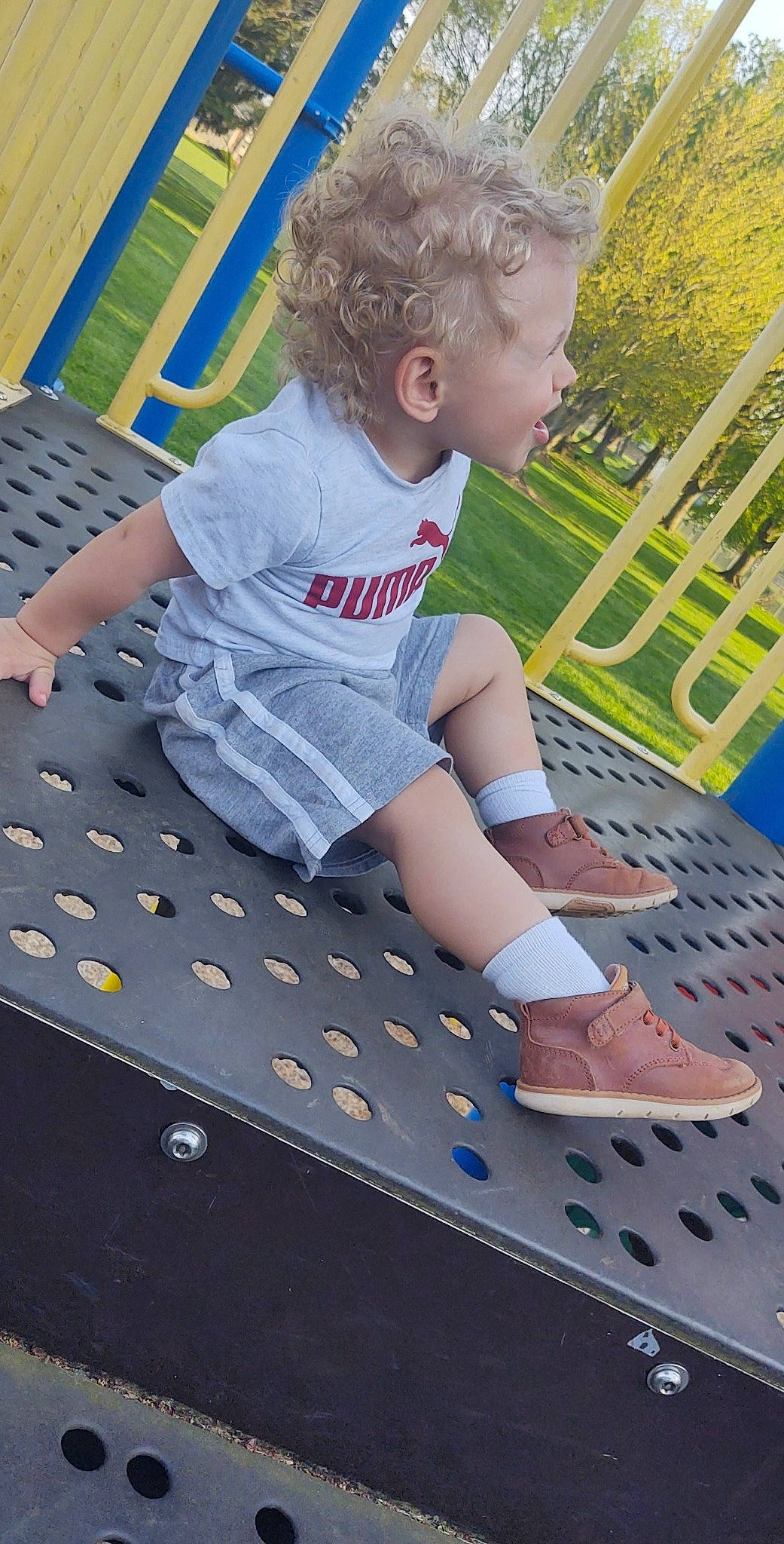 Derek is registered to the contest to win money with this photo: blue, child, city, fun, grass, leisure, outdoor_play_equipment, pattern, person, plant, playground, public_space, recreation, shoe, shorts, sneakers, t_shirt, thigh, toddler, tree