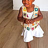 Nova joined the competition — help win amazing prizes! toddler, child, smiling, vest, crocheted, colorful, barefoot, white_skirt, curly_hair, hair_clips, indoor, wooden_floor, standing, cute, happy, person, portrait, playful, young_child, fashion