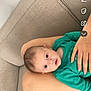 baby, infant, child, green_clothing, couch, arm, hand, skin, face, eyes, expression, comfort, indoor, person, young_child, resting, closeup, head, seated, casual