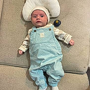 Maylonn a rejoint le concours — aidez-le/la à gagner de superbes lots ! baby, infant, overalls, hat, couch, pillow, pacifier, white_socks, baby_clothing, indoor, child, person, face, headwear, textile, furniture, relaxing, portrait, cute, small