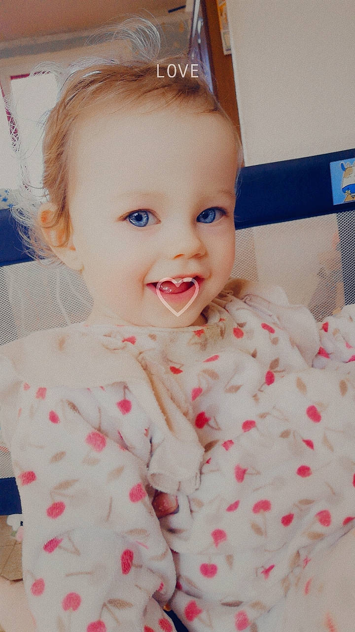 Lyana participe au concours pour gagner de l'argent avec cette photo : baby, baby_toddler_clothing, cheek, child, comfort, eye, eyelash, face, happy, head, iris, lip, nose, pattern, person, pink, skin, sleeve, smile, t_shirt