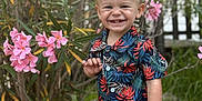 Eiden participe au concours pour gagner de l'argent avec cette photo : toddler, child, smile, happy, outdoor, flowers, pink_flowers, greenery, plants, nature, portrait, boy, shorts, shirt, patterned_clothing, grass, sunlight, baby, cute, garden