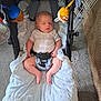 baby, infant, stroller, blanket, sleeping, indoor, car_seat, toy, soft_toy, carpet, child, clothing, seatbelt, comfort, resting, peaceful, floor, fabric, nap, cushion