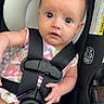 baby, infant, car_seat, child, straps, safety_harness, floral_dress, seat_padding, cute, wide_eyes, looking, indoors, young_child, person, small_hand, pink, black_straps, head_support, expression, secure