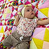 baby, infant, child, quilt, patchwork, colorful, headband, floral, clothing, pants, grass, outdoor, pattern, fabric, cute, portrait, lying_down, soft_texture, bright_colors, baby_girl