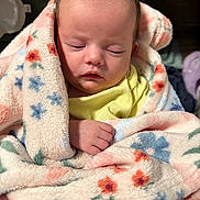 Alani is registered to the contest to win money with this photo: baby, sleeping, blanket, floral_pattern, soft_texture, cozy, infant, wrapped, hand, yellow_clothing, indoor, peaceful, cute, newborn, portrait, closeup, warm, comfort, resting, child