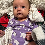 Alani joined the competition — help win amazing prizes! baby, infant, unicorn, onesie, purple_clothing, blanket, cozy, cute, child, face, human, newborn, skin, hand, expression, indoors, plush, soft, comfort, patch