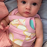 Alani is registered to the contest to win money with this photo: baby, infant, child, pink_clothing, flower_pattern, blanket, bed, cute, portrait, skin, hand, eyes, sitting, soft_texture, indoors, young_child, adorable, cozy, expression, person