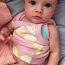 baby, infant, child, pink_clothing, flower_pattern, blanket, bed, cute, portrait, skin, hand, eyes, sitting, soft_texture, indoors, young_child, adorable, cozy, expression, person