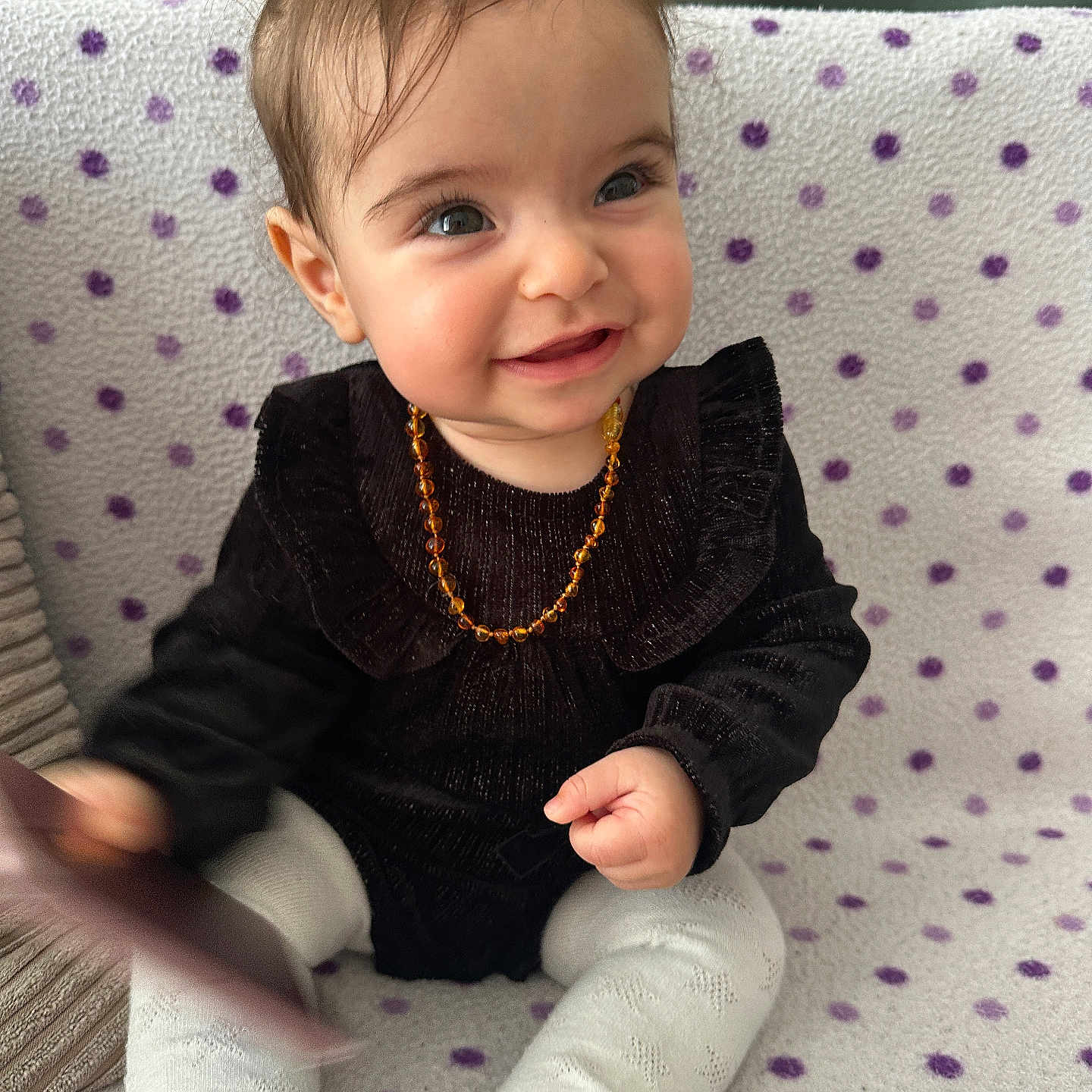 Mounia a rejoint le concours — aidez-le/la à gagner de superbes lots ! baby, black_clothing, blanket, child, cozy, cute, face, hand, happy, indoor, infant, necklace, pattern, person, polka_dot, portrait, sitting, smile, toy, white_tights