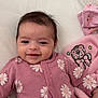 baby, infant, smiling, pink_onesie, daisy_pattern, blanket, plush_toy, soft_toy, lying_down, indoors, cute, child, face, happy, cozy, comfort, sleepy, toy, hand, head