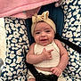 baby, smiling, headband, infant, seat, patterned_fabric, pink_towel, straps, clothing, cute, happy, child, indoor, portrait, person, sitting, baby_girl, closeup, baby_seat, hand