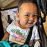 baby, child, smile, curly_hair, stroller, blanket, clothing, earring, face, infant, person, happy, portrait, seated, indoors, baby_toddler, cute, young_child, black_hair, skin