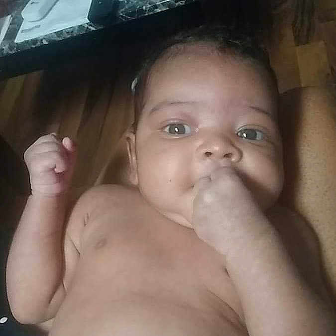 Kelleah is registered to the contest to win money with this photo: baby, infant, hand, face, diaper, skin, lying_down, indoor, table, remote_control, paper, cloth, floor, curious, child, person, young, closeup, portrait, arm