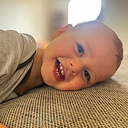 Ely participe au concours pour gagner de l'argent avec cette photo : child, toddler, smiling, face, teeth, lying_down, happy, indoor, texture, clothing, skin, head, eyes, mouth, person, baby, closeup, expression, cheerful, cozy