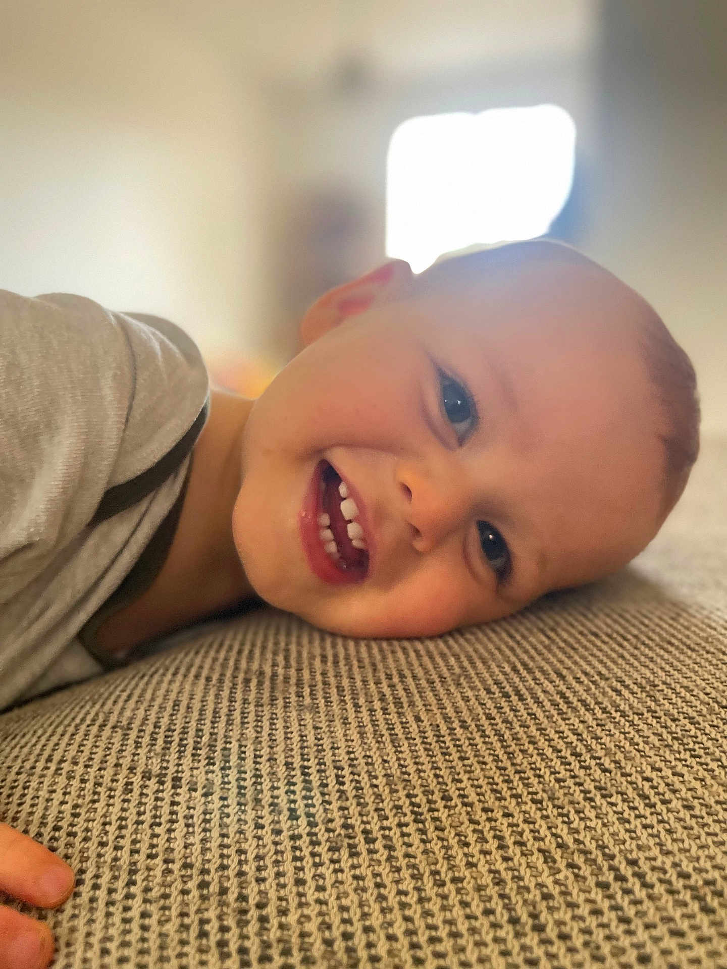 Ely participe au concours pour gagner de l'argent avec cette photo : child, toddler, smiling, face, teeth, lying_down, happy, indoor, texture, clothing, skin, head, eyes, mouth, person, baby, closeup, expression, cheerful, cozy
