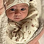 baby, infant, face, eyes, hat, clothing, blanket, floral_pattern, soft_texture, wrapped, cute, newborn, cozy, warm, portrait, indoors, child, person, headwear, sleepwear