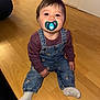 Ayaz is registered to the contest to win money with this photo: child, baby, toddler, pacifier, blue_pacifier, denim_overalls, striped_shirt, sitting, hardwood_floor, indoor, cute, smile, face, eyes, hair, sock, playroom, shelf, stuffed_animal, floor_texture