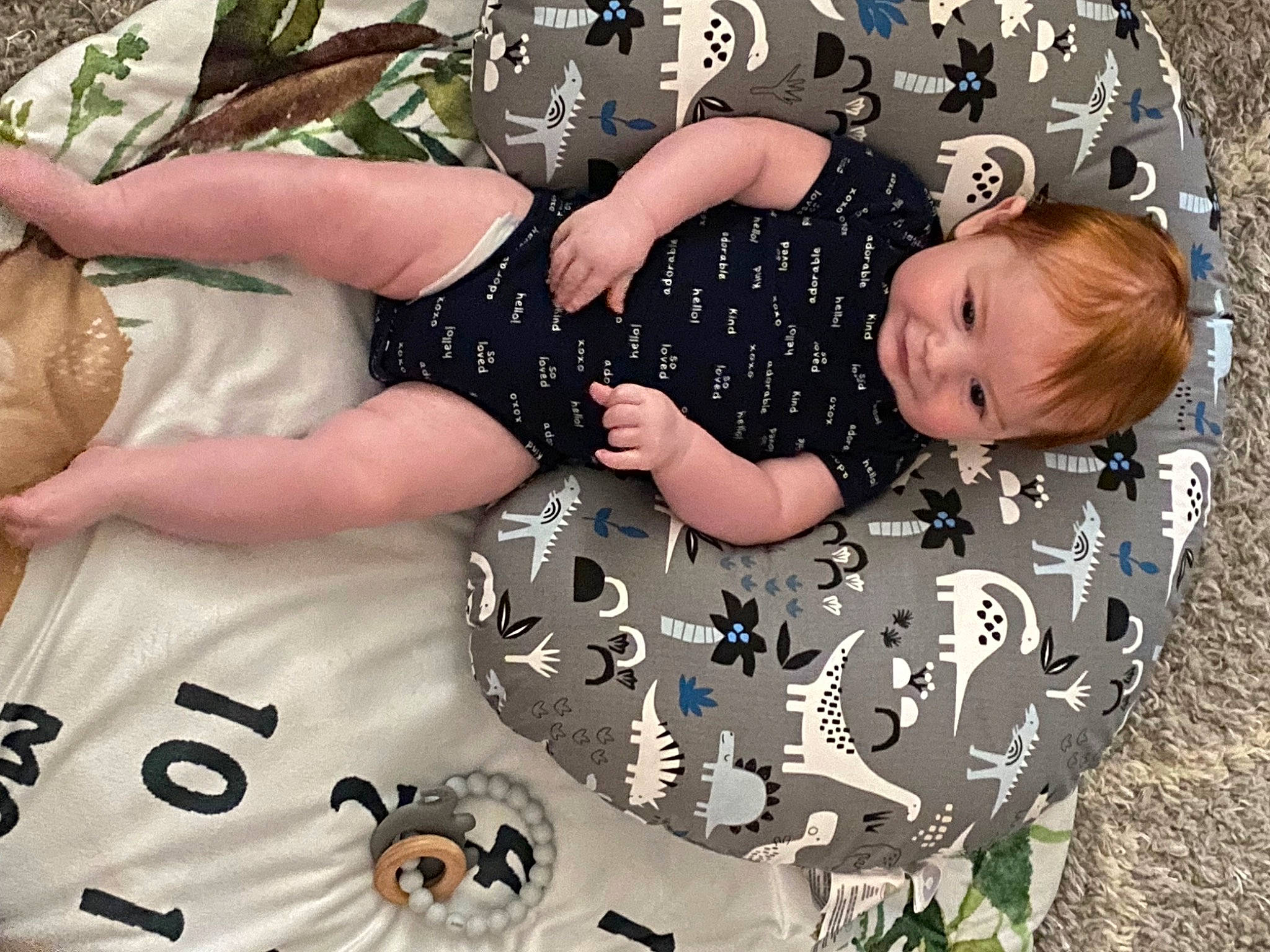 Kyle is registered to the contest to win money with this photo: arm, baby, baby_products, baby_toddler_clothing, child, circle, comfort, fashion_accessory, fun, grass, happy, pattern, people_in_nature, person, play, sitting, sleeve, t_shirt, textile, toddler