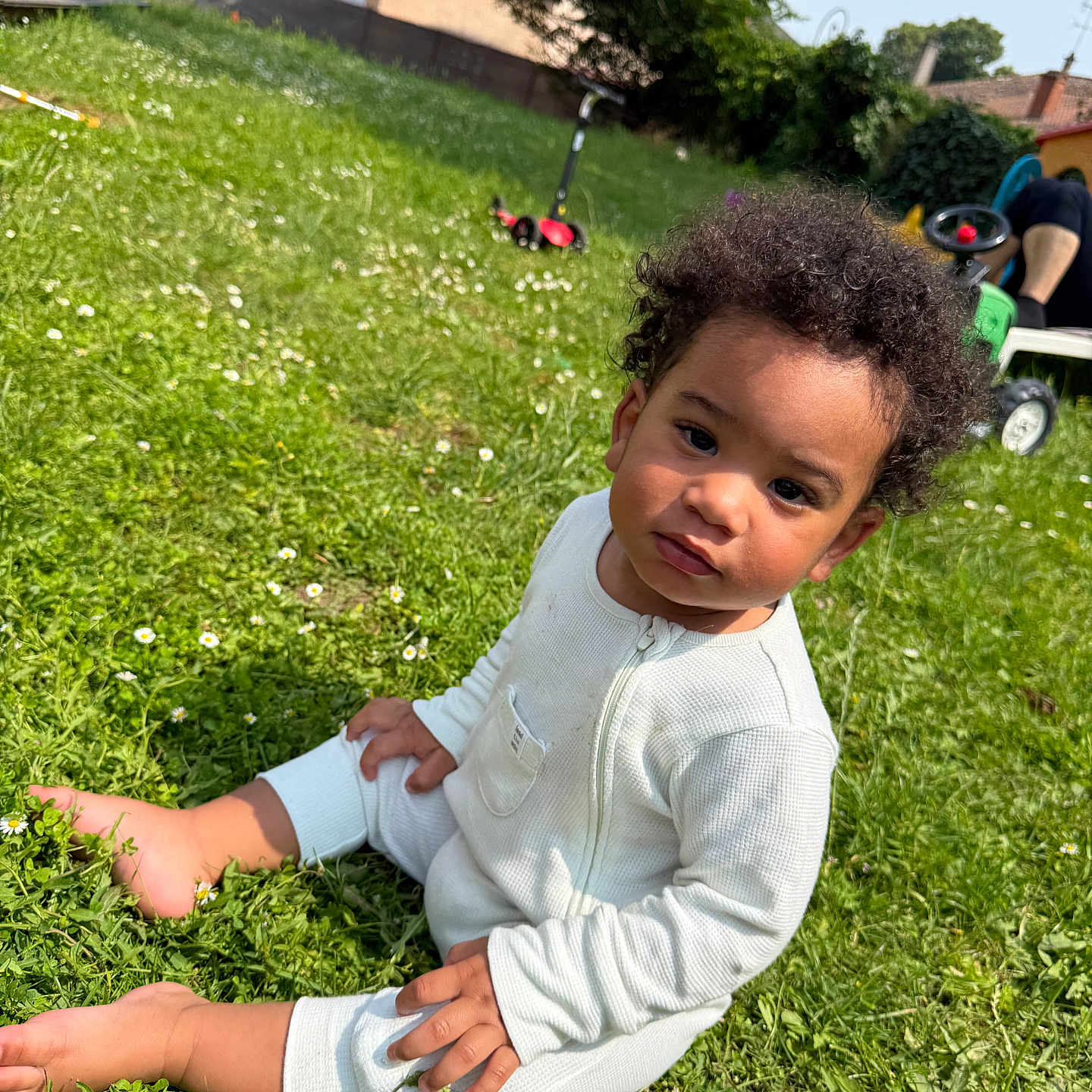 Harlow participe au concours pour gagner de l'argent avec cette photo : backyard, barefoot, casual, child, curly_hair, daylight, flowers, grass, greenery, nature, outdoor, person, playtime, portrait, sitting, summer, sunny, toddler, toy_scooter, white_onesie