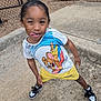 Nasir is registered to the contest to win money with this photo: child, playful, tongue_out, tshirt, yellow_shorts, sneakers, sidewalk, outdoor, fence, concrete, happy, person, cute, fun, summer, casual_clothing, young, smiling, standing, posing