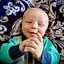 baby, smiling, happy, clapping, infant, face, child, blanket, pattern, cozy, cute, portrait, clothing, hand, skin, indoor, expression, young, head, comfort