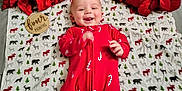 Remington is registered to the contest to win money with this photo: baby, infant, smiling, red_clothing, candy_cane_pattern, blanket, woodland_animals, poinsettia, flower, milestone_sign, four_months, holiday_theme, cute, lying_down, happy, tongue_out, festive, indoors, portrait, child