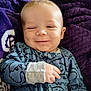 baby, smiling, onesie, blue_clothing, dinosaur_pattern, blanket, purple_blanket, infant, cute, happy, portrait, hand, face, child, cozy, sleepwear, young_child, lying_down, closeup, soft_texture