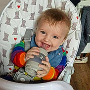 Alfred joined the competition — help win amazing prizes! baby, bib, blue_eyes, bottle, cheerful, chewing, child, colorful_clothing, elephant_pattern, face, happy, high_chair, home, indoor, infant, person, seatbelt, smile, toy, wooden_floor