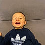 toddler, child, smiling, sweatshirt, adidas, clothing, couch, indoor, happy, portrait, person, young_child, casual, relaxed, head, face, furniture, home, sitting, joy