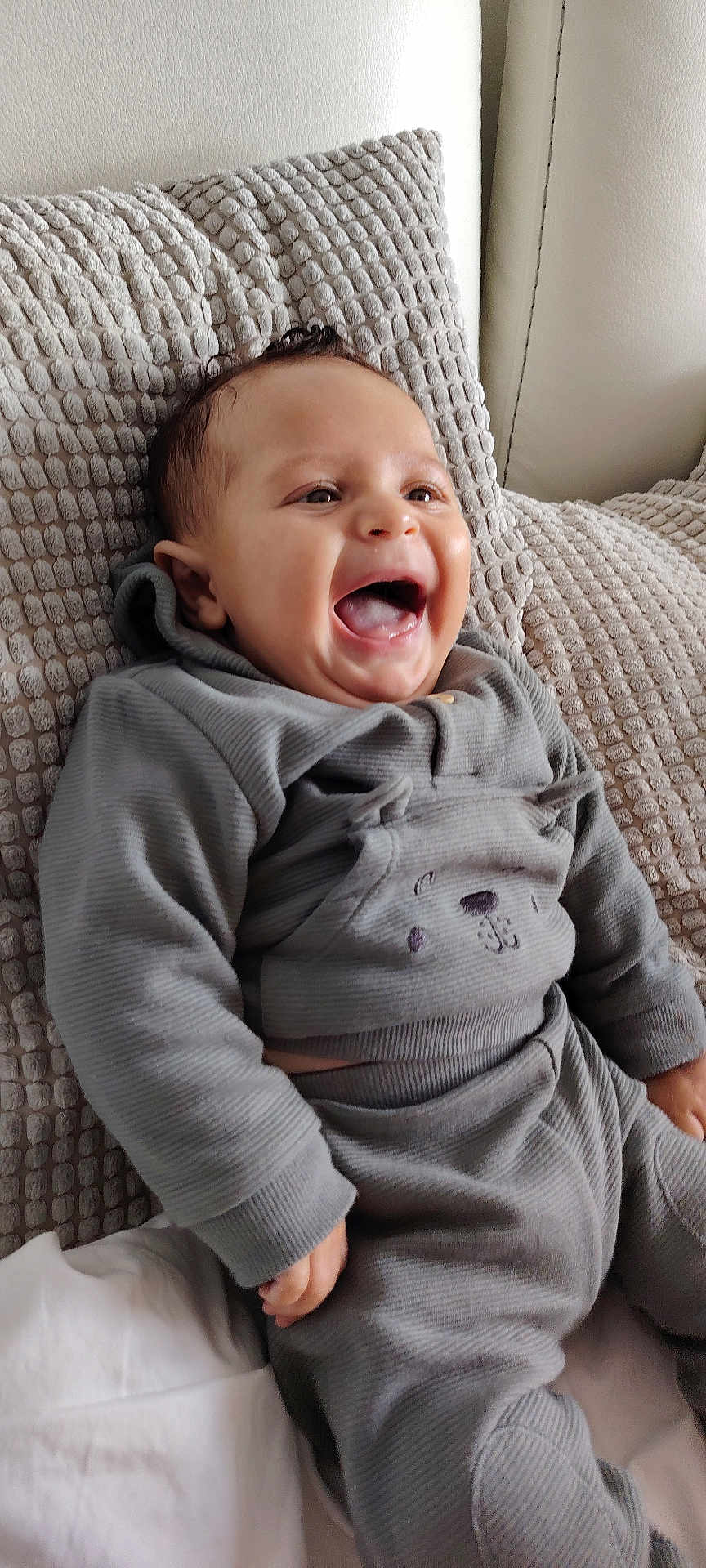 Jaden participe au concours pour gagner de l'argent avec cette photo : baby, child, laughing, smiling, pajamas, grey_clothing, cushion, texture, indoor, happy, infant, cute, portrait, person, head, face, hand, sitting, cozy, relaxed