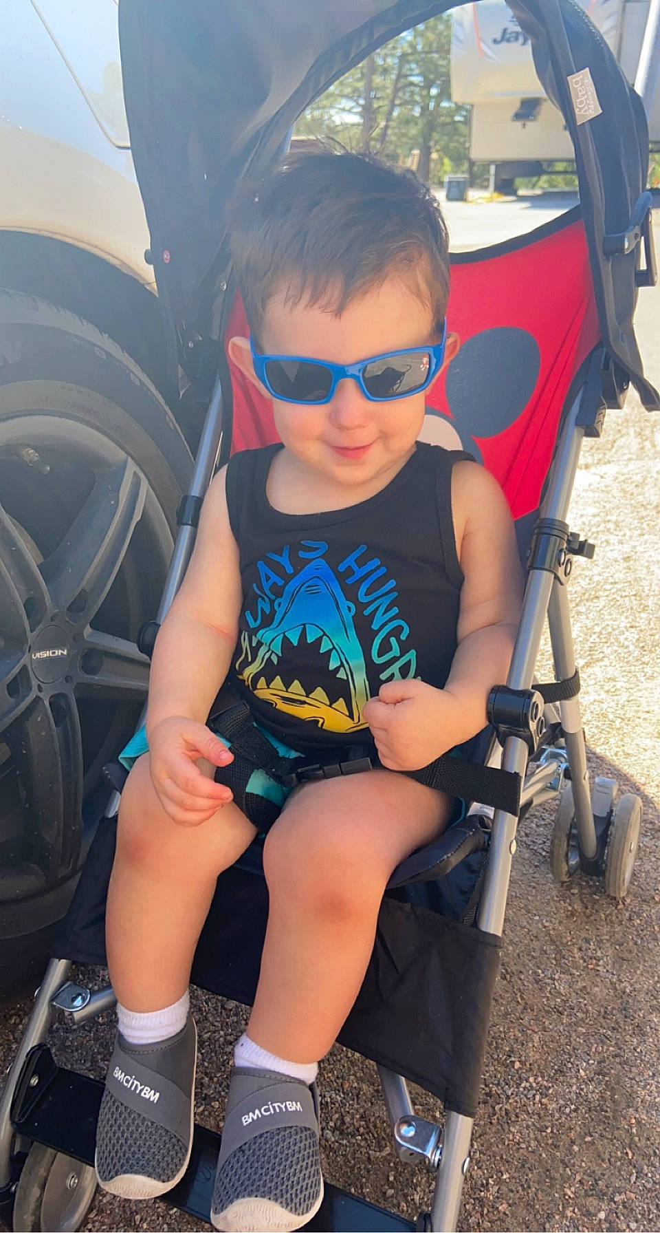 Cason is registered to the contest to win money with this photo: automotive_exterior, automotive_tire, cool, electric_blue, eyewear, fun, glasses, goggles, grass, hood, human_leg, leisure, person, shorts, sunglasses, thigh, tire, toddler, vehicle_door, vision_care
