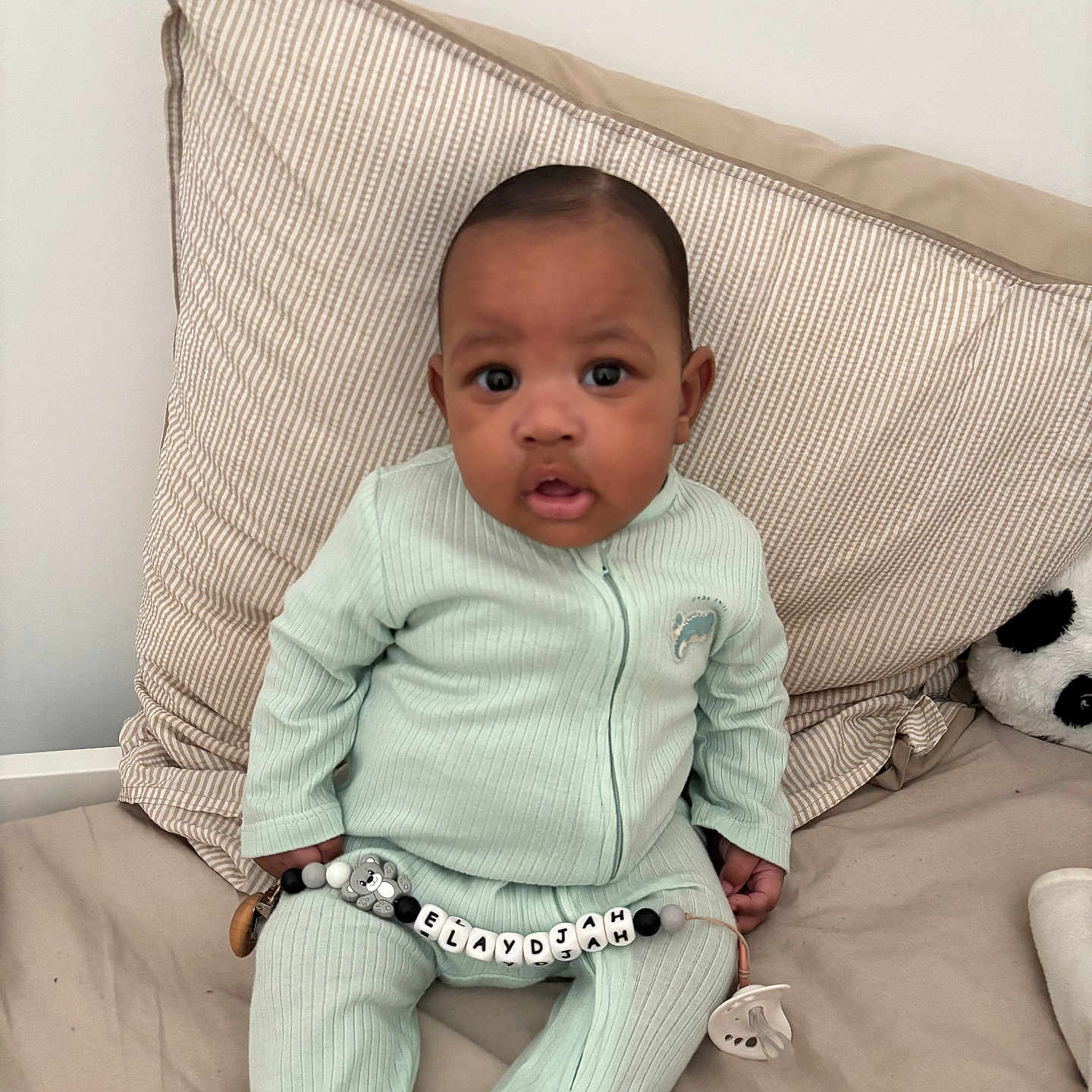 Elaÿdjah a rejoint le concours — aidez-le/la à gagner de superbes lots ! baby, infant, mint_green_clothing, striped_pillow, pacifier_clip, beads, personalized, panda_plush, bed, blanket, indoor, child, cute, sitting, curious, soft_lighting, nursery, portrait, young_child, cozy