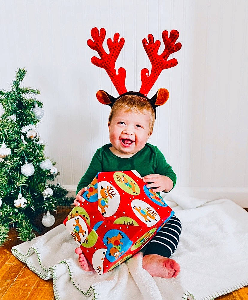 Jaxon is registered to the contest to win money with this photo: baby_toddler_clothing, christmas_decoration, christmas_ornament, christmas_tree, deer, event, fawn, gesture, happy, hat, head, holiday, holiday_ornament, human_body, ornament, person, product, red, sleeve, smile