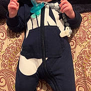 Emerson is registered to the contest to win money with this photo: baby, infant, hoodie, onesie, pacifier, bedspread, patterned, clothing, cute, lying_down, child, smiling, hands, feet, sock, fabric, indoors, person, face, expression