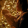 baby, adult, christmas_tree, smile, joy, warm_light, holiday, celebration, indoor, person, holding, profile, love, family, happy, glow, portrait, tenderness, festive, tshirt