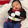 american_flag, baby, blanket, child, clothing, cute, face, flag, footwear, indoors, infant, military_style, newborn, outfit, person, portrait, resting, shoes, smiling, soft_texture