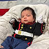 american_flag, baby, blanket, blue, clothing, cute, decor, face, flag, indoor, infant, laying_down, military_uniform, newborn, person, portrait, red, shoes, soft_texture, white