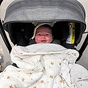 Nino participe au concours pour gagner de l'argent avec cette photo : animal_print, baby, blanket, canopy, car_seat, cheeks, fabric_pattern, headrest, hood, indoors, infant, newborn, portrait, seat, smile, smiling_face, soft_texture, stroller, swaddle, warning_label