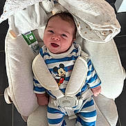 Nino participe au concours pour gagner de l'argent avec cette photo : baby, infant, smiling, mickey_mouse, onesie, harness, baby_bouncer, blanket, plush_toy, head, face, happy, striped_clothing, seatbelt, indoor, floor_tiles, close_up, newborn, cozy, awake