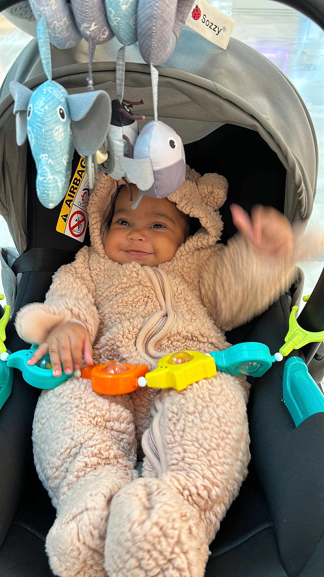 Jude a rejoint le concours — aidez-le/la à gagner de superbes lots ! baby, child, stroller, onesie, plush_toys, smiling, happy, infant, cute, soft_toys, playful, wearing_clothes, seated, indoors, colorful, toy_bar, baby_clothing, face, hands, cozy