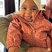 Jude participe au concours pour gagner de l'argent avec cette photo : baby, child, smiling, turban, jacket, pink, leopard_print, hand, adult, window, curtain, indoors, happy, face, clothing, holding, person, portrait, cute, warm