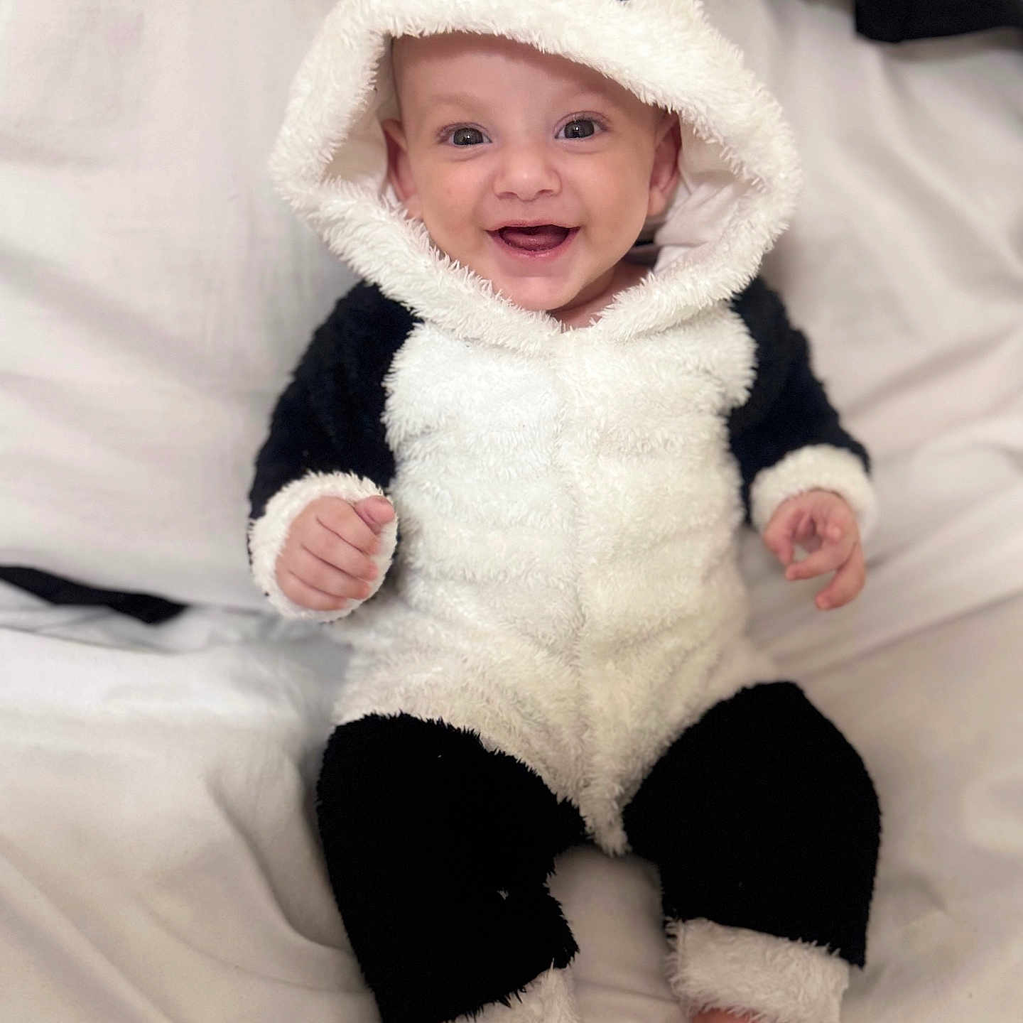 Youssef a rejoint le concours — aidez-le/la à gagner de superbes lots ! adorable, baby, black_and_white, child, costume, cute, feet, fuzzy, happy, hood, indoors, infant, onesie, panda_costume, playful, portrait, sitting, smiling, soft_fabric, white_bed