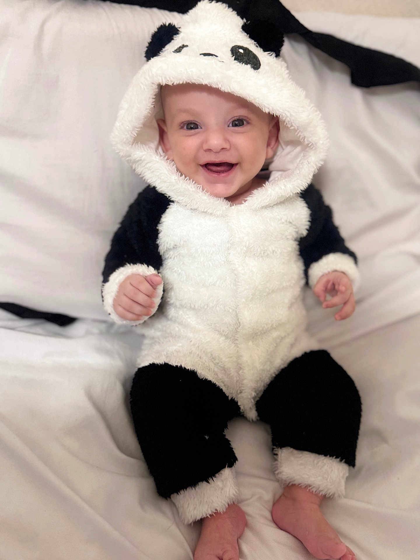 Youssef a rejoint le concours — aidez-le/la à gagner de superbes lots ! baby, panda_costume, smiling, sitting, onesie, cute, infant, white_bed, soft_fabric, happy, child, portrait, fuzzy, indoors, costume, black_and_white, feet, hood, playful, adorable