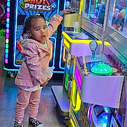 Akayla is registered to the contest to win money with this photo: arcade, arcade_machine, braided_hair, bright_lighting, child, claw_machine, colorful, electronic_game, entertainment_center, game_room, indoor, looking_at_camera, neon_lights, pink_outfit, portrait, prize_machine, reaching, sneakers, standing, toddler