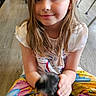 Kara joined the competition — help win amazing prizes! child, girl, sitting, floor, colorful_pants, white_shirt, animal, chick, pet, indoor, wooden_floor, smiling, young, casual, playful, hands, furniture, legs_crossed, person, cute