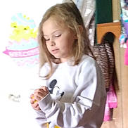 Kara is registered to the contest to win money with this photo: blonde_hair, blurry, casual, child, clothing, coat, curly_hair, focus, girl, hands, indoor, light, mickey_mouse, person, room, standing, sweatshirt, toy, wall_decor, young