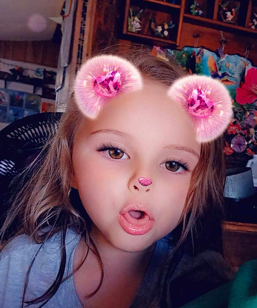 Kara is registered to the contest to win money with this photo: child, face, portrait, filter, pink, bear_ears, nose, sparkle, long_hair, expression, indoor, casual, selfie, young, cute, fun, playful, glossy_lips, brown_eyes, person